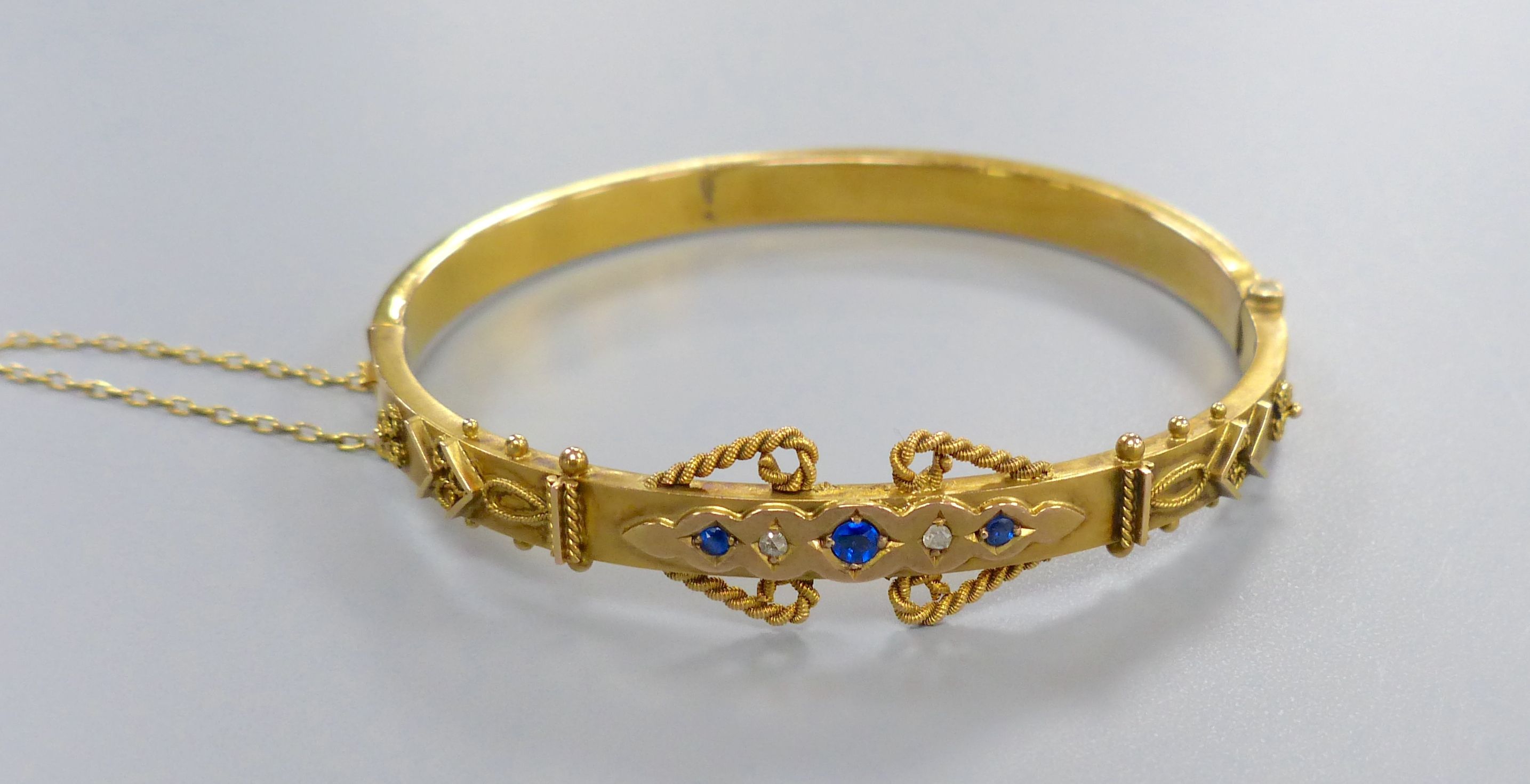 An Edwardian 9ct, sapphire and rose cut diamond chip set hinged bangle,
